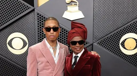 Getty Images Angelique Kidjo is pictured with US producer and musician Pharrell Williams at the Grammy Awards