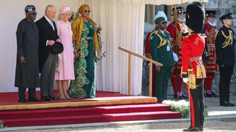 Getty Images King Charles, President Tinubu, Queen Camilla and First Lady  Oluremi Tinubu with other uniformed figures outside Windsor Castle