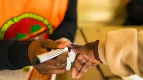 EPA A close-up as a polling agent marks a voter's thumbnail with indelible ink.