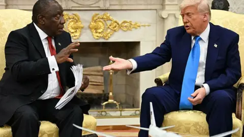 AFP via Getty Images President Donald Trump hands papers to South African President Cyril Ramaphosa during a meeting in the Oval Office of the White House in Washington, DC, on 21 May, 2025.
